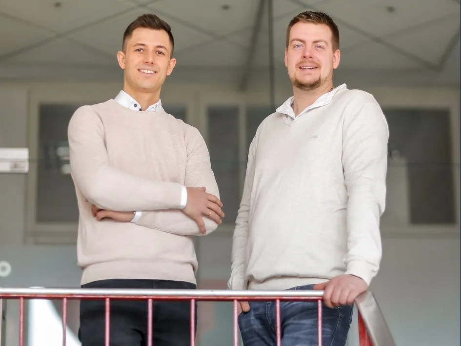 Henrik Dörr und Manuel Hasenauer in hellen Pullovern am Geländer