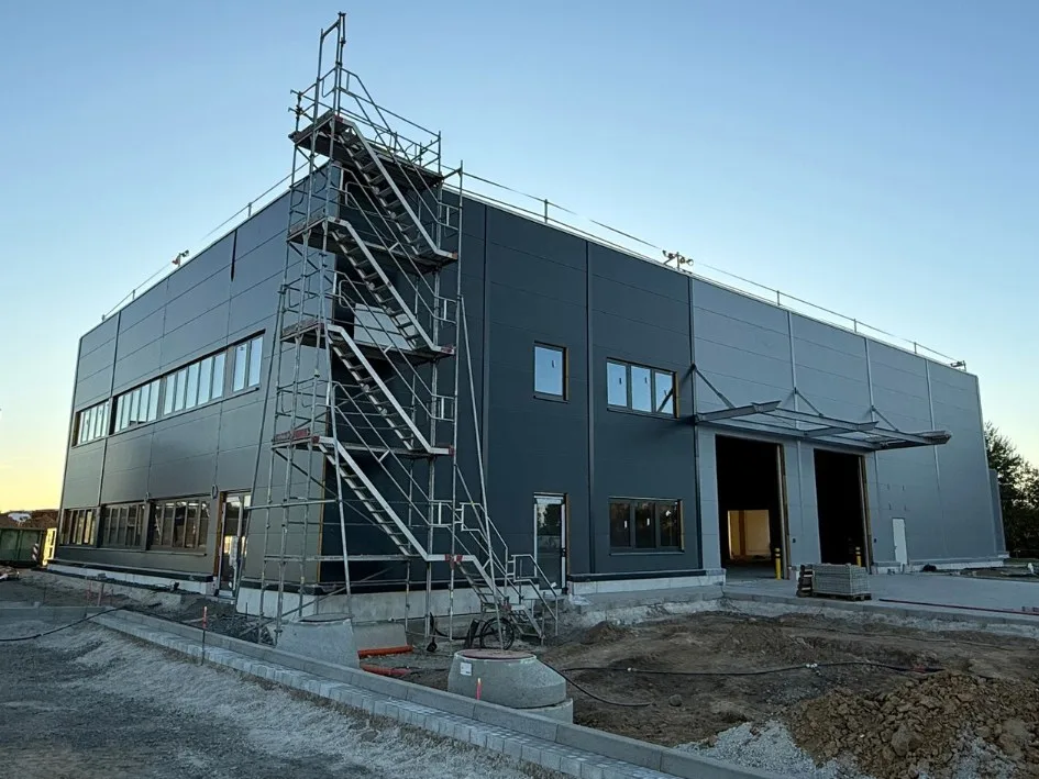 Der neue Firmenstandort im Bau, zweigeschossiger Hallenbau mit Gerüsttreppe